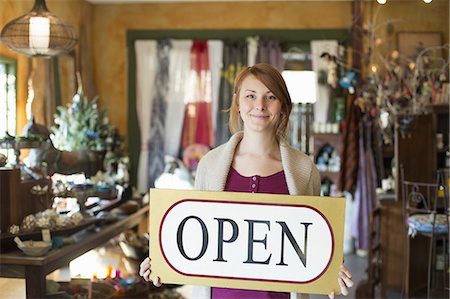 retro revival - A woman standing in an antique store, holding an OPEN sign. Displays of goods all around her. Stock Photo - Premium Royalty-Free, Code: 6118-07353588