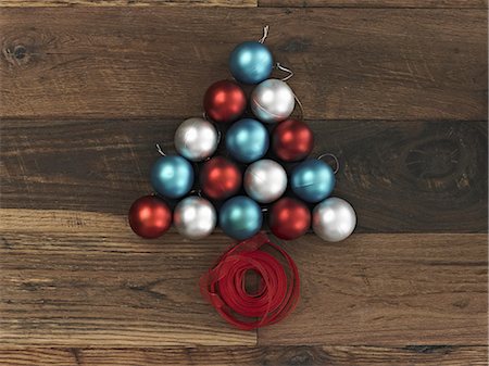 simsearch:6118-08521776,k - A collection of blue, red and silver ornaments arranged in a triangular shape on a wooden board. A Christmas tree shape with a red ribbon coiled at the base. Stock Photo - Premium Royalty-Free, Code: 6118-07353502