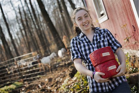 simsearch:6118-07731886,k - A young woman standing outside a dairy farm building holding two blocks of cheese. Stock Photo - Premium Royalty-Free, Code: 6118-07353756