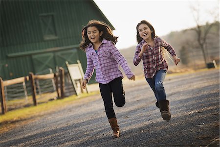 simsearch:693-05552824,k - Two children running along a road, by a farm building, on an organic farm. Stock Photo - Premium Royalty-Free, Code: 6118-07353773