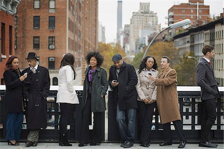 simsearch:6118-07121866,k - City life. A group of people on the go, keeping in contact, using mobile phones, and talking to each other. Standing in a line. Stock Photo - Premium Royalty-Free, Code: 6118-07353708