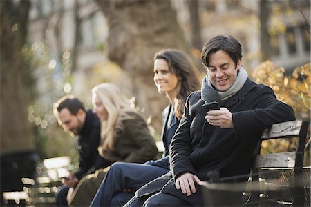Group on bench in urban park using smartphones Photographie de stock - Premium Libres de Droits, Code: 6118-07353895