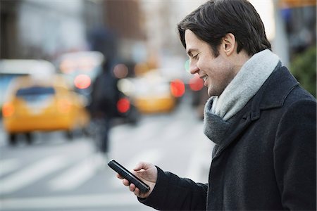 Man on busy street with smartphone Stock Photo - Premium Royalty-Free, Code: 6118-07353913