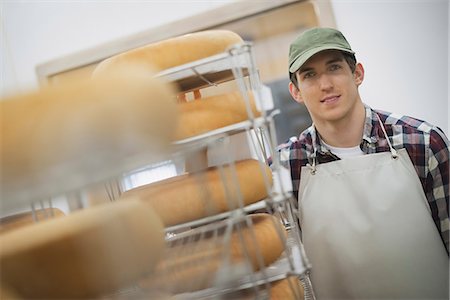 farmer male - A small organic dairy farm with a mixed herd of cows and goats. Dairy building with large wheels of cheese maturing. Trays of produce. Stock Photo - Premium Royalty-Free, Code: 6118-07353919