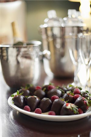 Wedding dessert. Plate of hand-dipped organic strawberries, fruit in artisinal handmade chocolate with raspberry garnish. Champagne and glasses. Photographie de stock - Premium Libres de Droits, Code: 6118-07354052