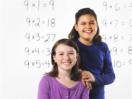 simsearch:632-03898264,k - Two girls  looking at a series of mathematical multiplication tables on a see through clear wall with black pen. Learning. Foto de stock - Sin royalties Premium, Código: 6118-07354254