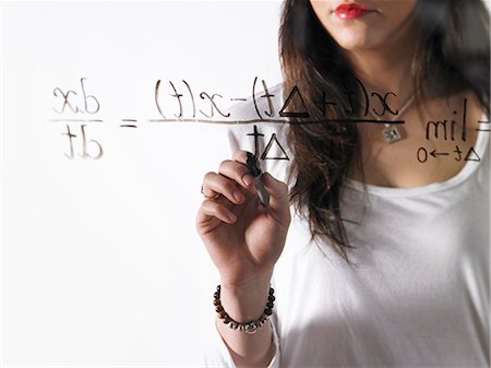 simsearch:632-03898264,k - A young woman writing a mathematical equation with black marker on a clear seethrough surface. Foto de stock - Sin royalties Premium, Código: 6118-07354227