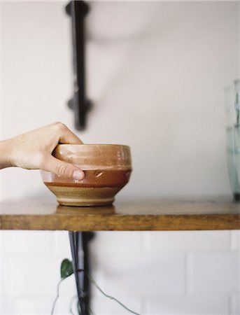 simsearch:6118-07354433,k - Farm to Table. A person reaching up for a pottery bowl in a domestic kitchen. Stock Photo - Premium Royalty-Free, Code: 6118-07354383