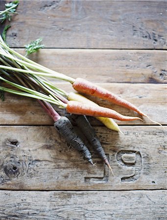 simsearch:6118-08521776,k - A domestic kitchen table with a worn scrubbed surface. A bunch of fresh carrots. Stock Photo - Premium Royalty-Free, Code: 6118-07354387