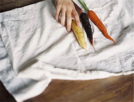 simsearch:6118-07352741,k - A domestic kitchen table. A person arranging fresh carrots on a white cloth. Stock Photo - Premium Royalty-Free, Code: 6118-07354388