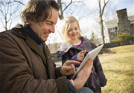 simsearch:6118-07351124,k - An Organic Farm in Winter in Cold Spring, New York State.  A man holding a digital tablet in his hands, showing his child the screen. Stock Photo - Premium Royalty-Free, Code: 6118-07354446