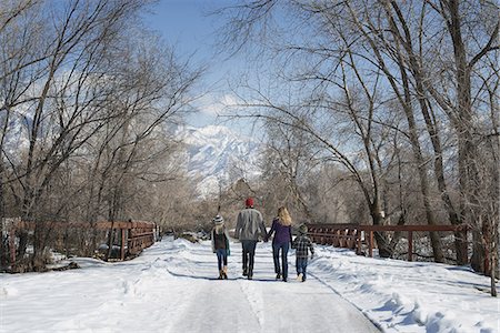 simsearch:6118-07354445,k - Winter scenery with snow on the ground. A family, adults and two children, walking down an empty road. Stock Photo - Premium Royalty-Free, Code: 6118-07354455