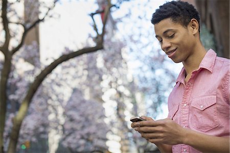 simsearch:6118-07354515,k - City life. A young man in the park in spring, using a mobile phone. Stock Photo - Premium Royalty-Free, Code: 6118-07354497