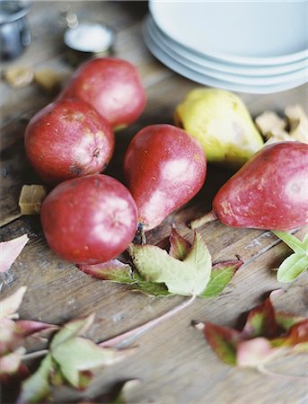 A domestic kitchen tabletop. A small group of fresh organic pears and a stack of white plates. Stock Photo - Premium Royalty-Free, Code: 6118-07354433