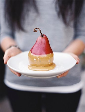 simsearch:6118-07354433,k - A woman holding a plate with a dessert of fresh organic pear dipped in fudge sauce. Stock Photo - Premium Royalty-Free, Code: 6118-07354435