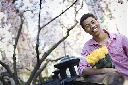 simsearch:6118-07354515,k - City life. A young man in the park in spring, holding a bunch of yellow roses. Stock Photo - Premium Royalty-Free, Code: 6118-07354501