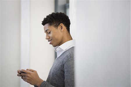 simsearch:6118-07354515,k - A young man in a grey sweater using his mobile phone. Stock Photo - Premium Royalty-Free, Code: 6118-07354515