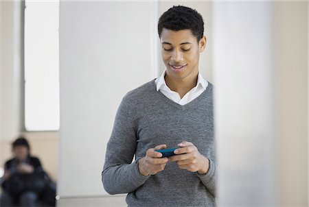 simsearch:6118-07354515,k - A young man in a grey sweater using his mobile phone. Stock Photo - Premium Royalty-Free, Code: 6118-07354516