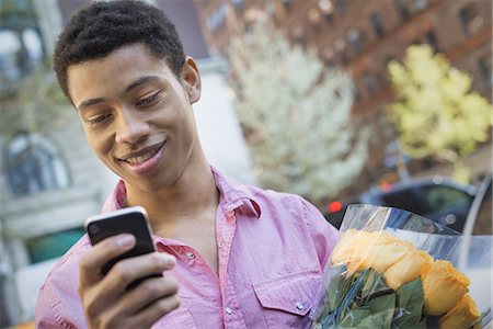 simsearch:6118-07354515,k - Urban Lifestyle. A young man with short black hair, wearing a pink casual shirt. Holding a smart phone. Stock Photo - Premium Royalty-Free, Code: 6118-07354537