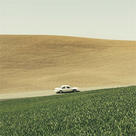 A car driving on am uphill slope, surrounded by farmland and lush, green fields of wheat, near Pullman, Washington. Stock Photo - Premium Royalty-Free, Code: 6118-07354619