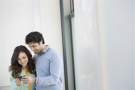 simsearch:6118-07354515,k - Urban Lifestyle. A young couple, man and woman side by side, looking at a mobile phone. Stock Photo - Premium Royalty-Free, Code: 6118-07440877