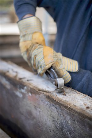 A reclaimed lumber workshop. A man preparing the timber by removing all the nails and studs. Stock Photo - Premium Royalty-Free, Code: 6118-07439798