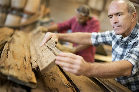 decay (organic) - A reclaimed lumber workshop. A group of people working. A man measuring and checking planks of wood for re-use and recycling. Stock Photo - Premium Royalty-Free, Code: 6118-07439802