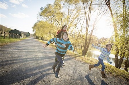 running in the fall - A woman and two children running by a lake, at an animal sanctuary. Autumn. Foto de stock - Sin royalties Premium, Código: 6118-07439818