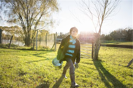 simsearch:6118-07353446,k - A young boy in an animal paddock, holding a bucket of feed. Animal sanctuary. Stock Photo - Premium Royalty-Free, Code: 6118-07439820