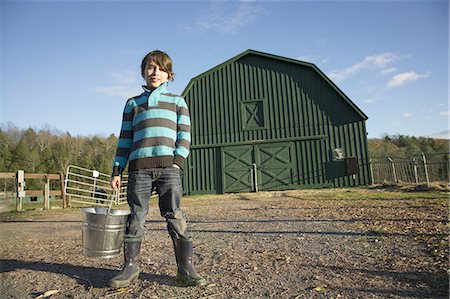 simsearch:6118-07353446,k - A young boy in an animal paddock, holding a bucket of feed. Animal sanctuary. Stock Photo - Premium Royalty-Free, Code: 6118-07439821