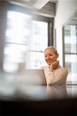 Office life. A woman seated using a laptop computer. Stock Photo - Premium Royalty-Free, Code: 6118-07769486