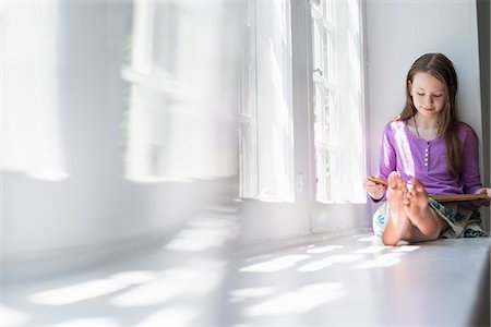 Girl sitting by a window, reading a book. Stock Photo - Premium Royalty-Free, Code: 6118-07769579