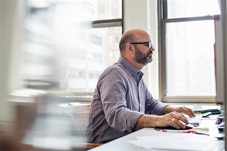 sleeve - Office life. A man sitting at a desk using a computer, looking intently at the screen. Stock Photo - Premium Royalty-Free, Code: 6118-07769525