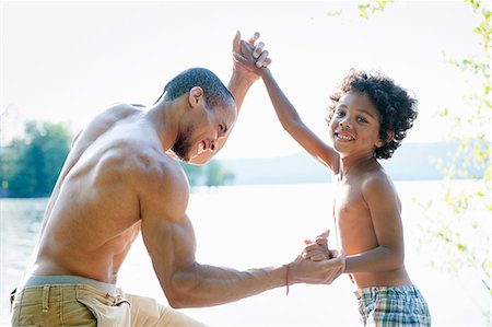 roughhousing - Father playing with his son, wrestling with him by a lake. Stock Photo - Premium Royalty-Free, Code: 6118-07781788