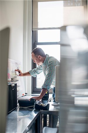 Office life. A man standing up working and making notes on a wall chart. Project management. Stock Photo - Premium Royalty-Free, Code: 6118-07781700