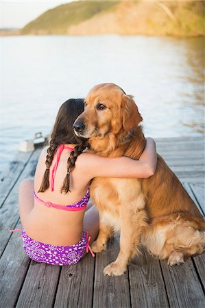 A young girl and a golden retriever dog sitting on a jetty. Photographie de stock - Premium Libres de Droits, Code: 6118-07731782