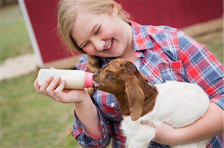 A girl bottle-feeding a baby goat. Stock Photo - Premium Royalty-Free, Code: 6118-07731886