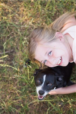 A girl hugging a black and white dog in the park. Stock Photo - Premium Royalty-Free, Code: 6118-07731967