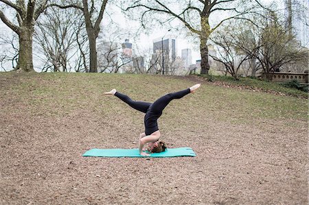 simsearch:6118-07731916,k - A young woman in Central Park, in a black leotard and leggings, doing yoga. Photographie de stock - Premium Libres de Droits, Code: 6118-07731914