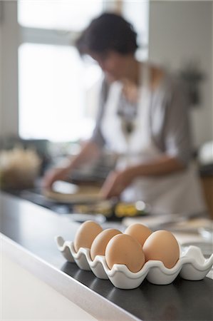 simsearch:6118-08521776,k - A woman cooking at a kitchen table. A tray of hen's eggs. Stock Photo - Premium Royalty-Free, Code: 6118-07808972