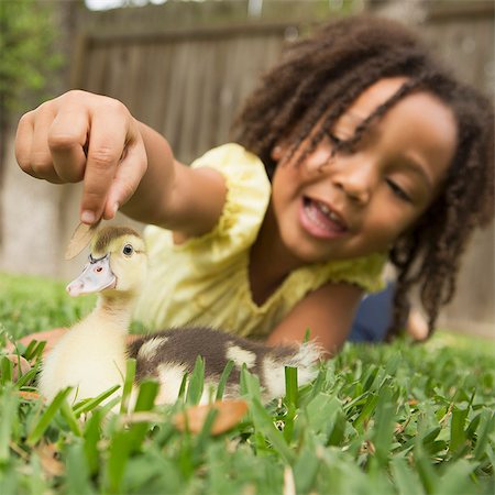 stroke - A young girl lying on the grass stroking the head of a duckling. Stock Photo - Premium Royalty-Free, Code: 6118-08081870