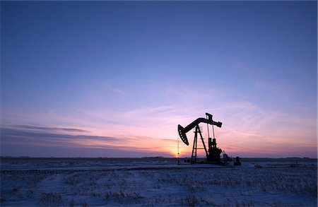 An oil drilling rig and pumpjack on a flat plain in the Canadian oil fields at sunset. Stock Photo - Premium Royalty-Free, Code: 6118-08023708