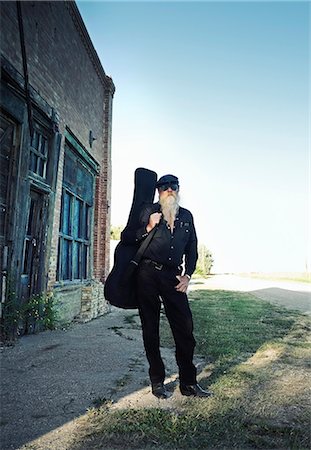 stringed instruments - A man carrying a guitar. Stock Photo - Premium Royalty-Free, Code: 6118-08023804