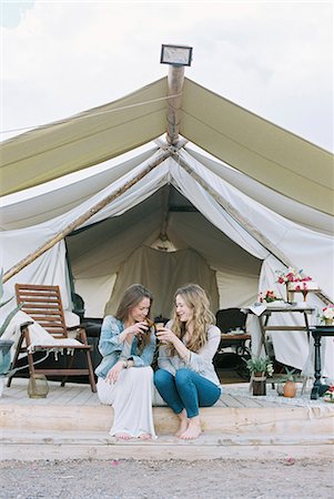 simsearch:6118-08399701,k - Two smiling women sitting outside a large tent laughing and having a glass of wine. Stock Photo - Premium Royalty-Free, Code: 6118-08140150