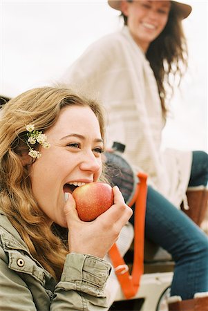 Two young women, one biting into an apple. Stock Photo - Premium Royalty-Free, Code: 6118-08140169