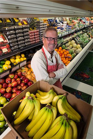 picture of apples in grocery store - A man standing in a grocery shop beside a display of fresh fruits and vegetables. Stock Photo - Premium Royalty-Free, Code: 6118-08140115