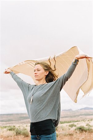 simsearch:6118-08140197,k - Woman standing in a desert with her arms raised, holding a wrap which is fluttering in the wind. Stock Photo - Premium Royalty-Free, Code: 6118-08140229