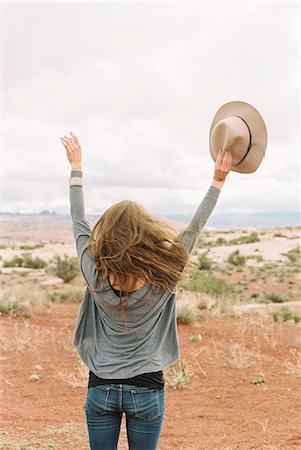 simsearch:6118-08140197,k - Rear view of a woman standing in the desert, holding a hat, her arms raised up in the air. Stock Photo - Premium Royalty-Free, Code: 6118-08140231