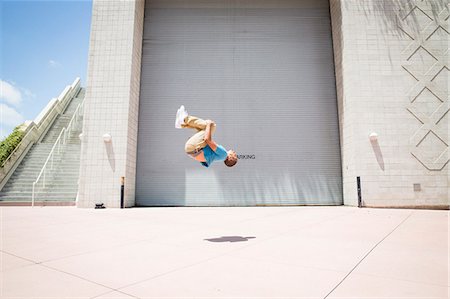 Young man somersaulting in front of a garage door. Stock Photo - Premium Royalty-Free, Code: 6118-08129691