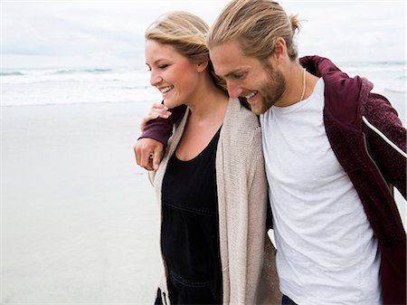 simsearch:6118-08129648,k - Young man and young woman walking on a beach, smiling. Foto de stock - Sin royalties Premium, Código: 6118-08129702